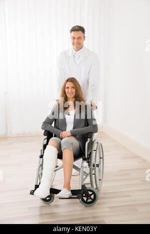 Männlicher Arzt helfen Ihnen gerne Frau sitzt im Rollstuhl Stockfoto