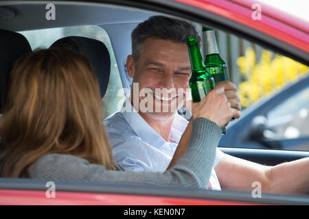 Close-up happy Reifes Paar im Auto sitzend Bier genießen. Stockfoto