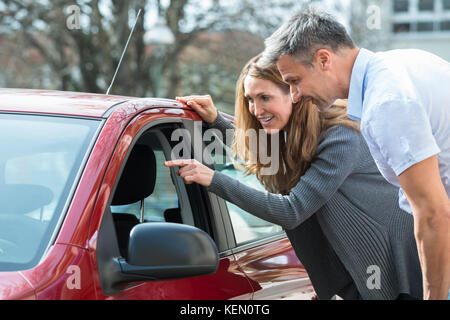 Glückliches Paar an neuen roten Auto Auto Salon suchen Stockfoto