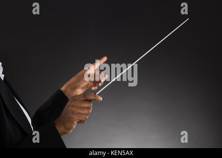 In der Nähe der weiblichen Orchester Dirigent holding Baton auf schwarzem Hintergrund Stockfoto