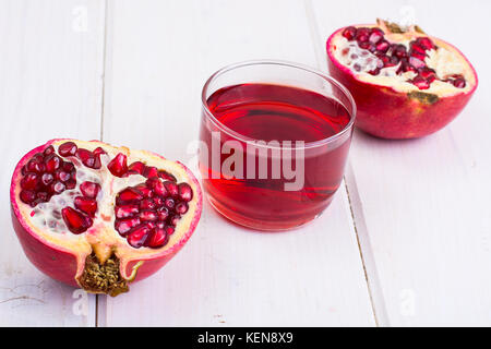 Granatapfel und Saft im Glas auf weißem Holz- Hintergrund. studio Foto Stockfoto