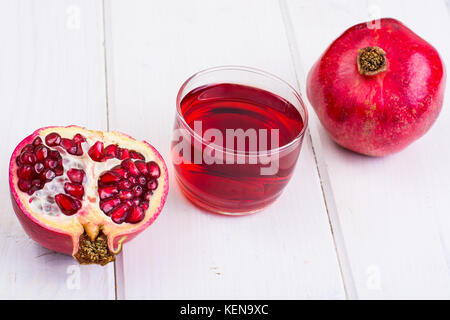 Granatapfel und Saft im Glas auf weißem Holz- Hintergrund. studio Foto Stockfoto