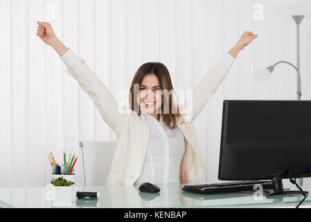 Erfolgreiche Geschäftsfrau ihre Arme heben im Büro Stockfoto