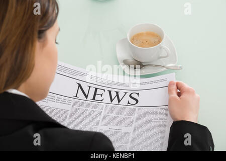 Nahaufnahme der Geschäftsfrau lesen Zeitung mit Tasse Kaffee auf Schreibtisch Stockfoto