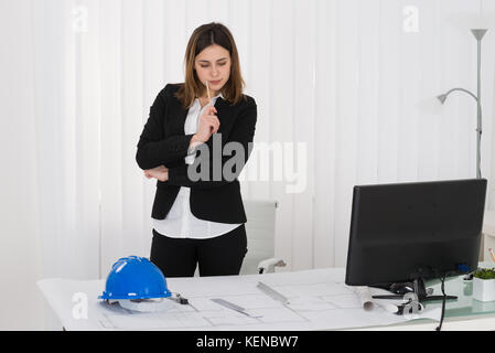 Junge weibliche Architekten arbeiten auf Blau Drucken im Büro Stockfoto