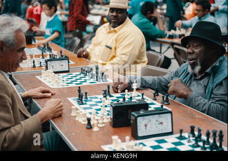 Alte afrikanische amerikanische älterer Mann Freizeitgestaltung durch Schach spielen im Central Park mit einer ethnischen Gruppe von Freunden. Stockfoto