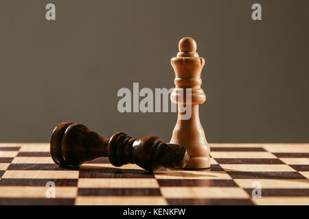 Weiß chess Queen, stehend über schwarzen König, in einer Holz- Schachbrett, Stockfoto