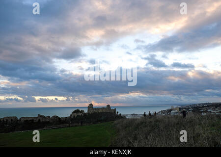 Hastings, East Sussex, 22. Okt 2017. Am Ende des Sturms Brian und, nach einem sonnigen Tag, einem Windgepeitschten Sonnenuntergang über Hastings Castle und mit schweren Gewitterwolken über der fernen Beachy Head. Stockfoto