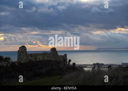 Hastings, East Sussex, 22. Okt 2017. Am Ende des Sturms Brian und, nach einem sonnigen Tag, einem Windgepeitschten Sonnenuntergang über Hastings Castle und mit schweren Gewitterwolken über der fernen Beachy Head. Stockfoto