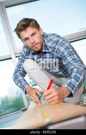 Mann messen Holzbohlen mit Klebeband und Bleistift Stockfoto