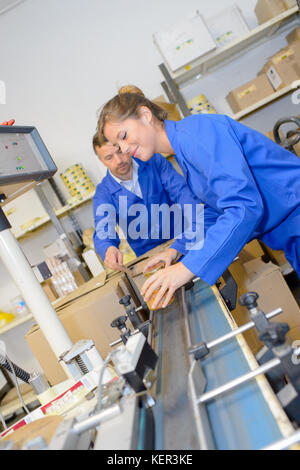 Arbeiter packen Pakete mit Klebeband im Lager Stockfoto