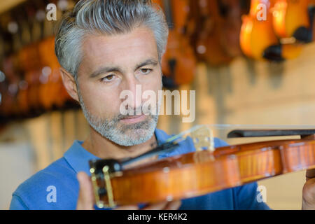 Mann mit der Prüfung einer Violine Stockfoto