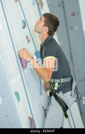 Junger Mann klettern eine Wand Stockfoto