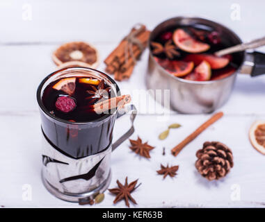 Glühwein in ein Glas mit einem Bügeleisen Becherhalter an einer weißen Holz- Hintergrund, Ansicht von oben Stockfoto