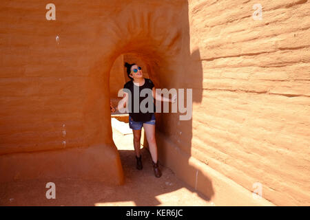 Eine junge Frau schaut mit Staunen durch eine Passage in den Ruinen einer alten Mission im Pecos National Historic Park in der Nähe von Santa Fe, New Mexico. Stockfoto