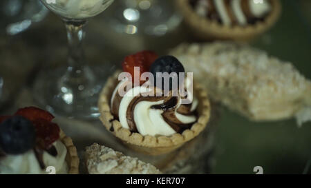 Leckere Cupcakes mit Beeren. Schokoladen-Cupcakes, dekoriert mit Creme Rose mit Herz. Schokoladen-Cupcakes dekoriert mit Creme Rose mit Herz HD Stockfoto