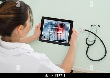 Junge Ärztin auf zahnmedizinische Röntgensysteme auf digitalen Tablet in der Klinik Stockfoto