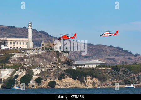 Ein paar der Küstenwache MH-65 Dolphin Helikopter der Air Station San Francisco fliegen in der Nähe von Alcatraz in der Bucht von San Francisco. Stockfoto