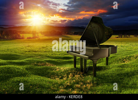 Schwarzes Hochglanz-Klavier auf der Wiese unter dem dramatischen Himmel mit sonnigen Lichtern. Fotomontage mit 3D-Rendering-Illustration. Stockfoto