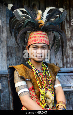 Ein junger Mann in der Iban Krieger headhunter Regalia, einschließlich hornbill Federkopfschmuck in Sarawak Cultural Village. Stockfoto