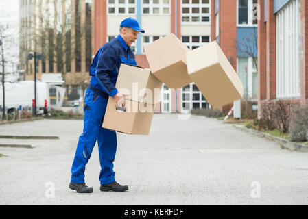 Delivery Man mit fallenden Stapel von Kisten auf der Straße Stockfoto