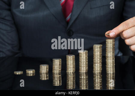 Nahaufnahme der Geschäftsmann hand Münzen auf der Münzen auf dem Schreibtisch stapeln Stockfoto