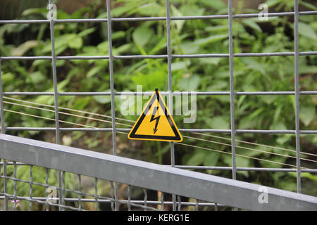 Gelbes Dreieck Warnschild an einem elektrischen Zaun Stockfoto