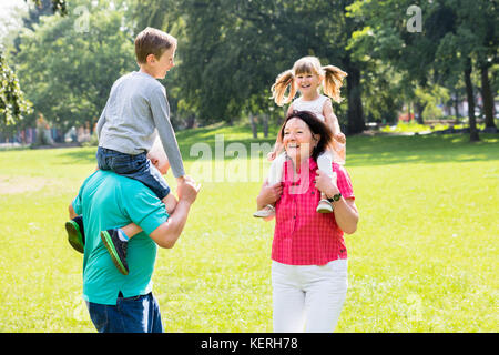 Gerne alten Großeltern, piggyback Fahrt zu ihrem Enkel in Park Stockfoto