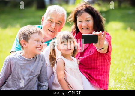 Glückliche Familie Selfie mit Telefon im Park Stockfoto