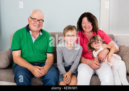 Glückliche Familie mit Brille, während auf der Couch zusammen zu Hause sitzen Stockfoto