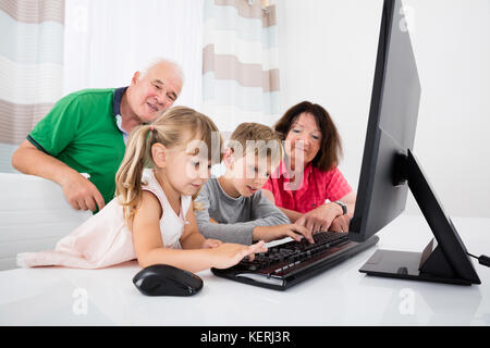 Glückliche Großeltern Spielen mit Kindern auf Laptop Stockfoto