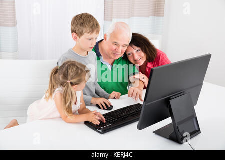 Großeltern lernen zu verwenden Desktop Computer von Kindern zu Hause. Stockfoto
