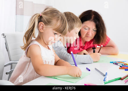 Großmutter an Kinder Zeichnung Auf buntes Papier zu Hause Suchen Stockfoto