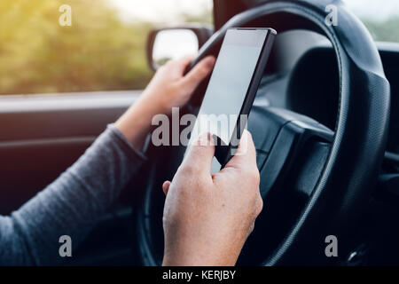 Frau fahren und Textnachrichten auf mobile Smartphones. Halten Sie das Lenkrad Stockfoto