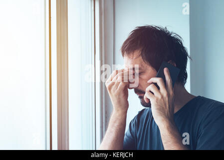 Unangenehmen Anruf, besorgt, ängstlich Mann mit jemand auf dem Mobiltelefon Stockfoto