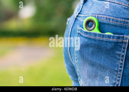 Grüne spinner Toy für Nerv liegt in einer Tasche auf dem Hintergrund des grünen Grases Stockfoto