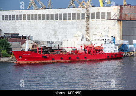 Red cargo Schiff in den Hafen. Container mit Waren beladen auf einem kommerziellen Schiff mit einem Kran in den Hafen der Stadt-/entladen. Business Transport Stockfoto