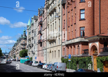 Blick auf die Straße mit einem klassischen schwedischen Häuser, skandinavischen Stil aus rotem Backstein und gelben Putz, die Autos auf der Straße geparkt, Stadtzentrum Stockfoto