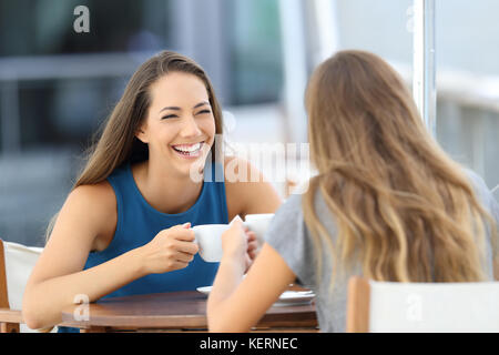 Zwei glückliche Freunde sprechen und lachen sitzen in einem Restaurant Terrasse Stockfoto