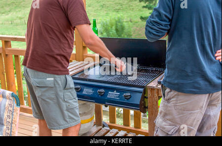 Zwei Männer am Grill während der Reinigung der Gitter Stockfoto