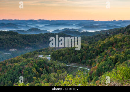 Im Frühherbst schlängelt sich eine Straße durch einen Appalachischen Wald. Stockfoto