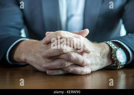 Nahaufnahme der Geschäftsmann halten Hände mit den Fingern auf dem Tisch gekreuzt Stockfoto