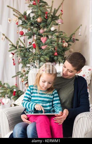 Mutter und Tochter mit Tablet-PC in der Nähe von Weihnachten Baum Stockfoto