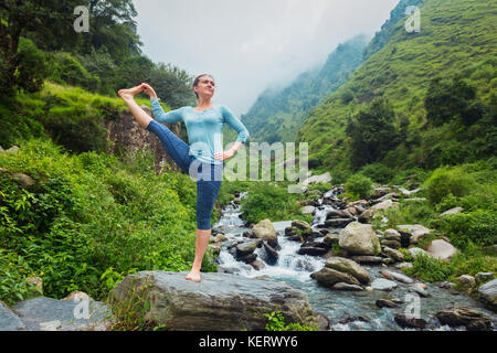 Frau tut Ashtanga Vinyasa Yoga Asana im Freien am Wasserfall Stockfoto