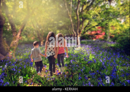 Kinder gehen Hand in Hand durch Bluebell Woods Stockfoto