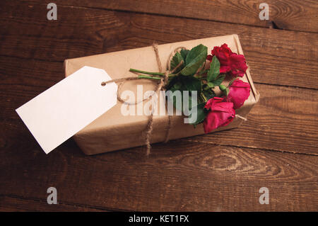 Geschenk verpackt in Kraftpapier mit Rose Blume auf der Oberseite Stockfoto