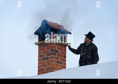 Schornsteinfeger im Winter auf einem Dach mit rauchigen Schornstein, Oberbayern, Bayern, Deutschland Stockfoto