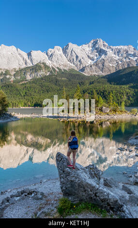 Wanderer steht auf Felsen, in die Ferne schaut, See Eibsee und Zugspitze, Wettersteingebirge, in der Nähe von Grainau, Oberbayern Stockfoto