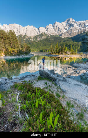 Wanderer steht auf Felsen, in die Ferne schaut, See Eibsee und Zugspitze, Wettersteingebirge, in der Nähe von Grainau, Oberbayern Stockfoto