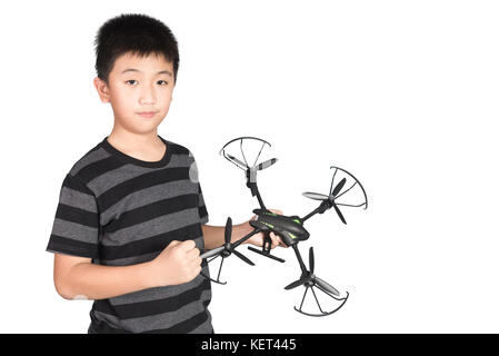 Erfolgreicher glücklicher und attraktiver asiatischer Junge, der hexacopter Drohne hält und mit seiner Faust auf weißem Hintergrund isoliert in die Luft stanzt. Stockfoto